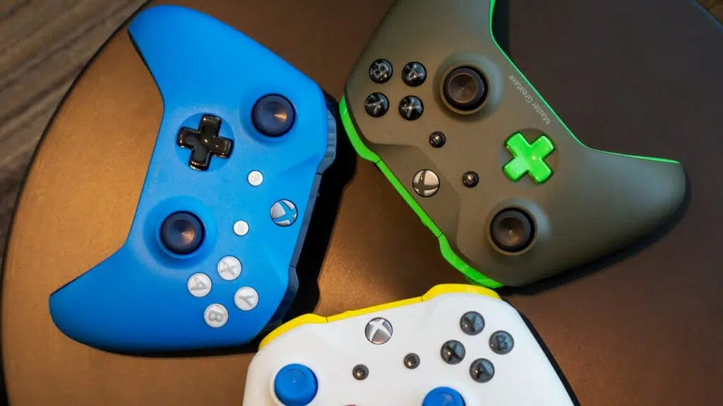 Três controles da versão xbox one s, nas cores azul, branco e verde.