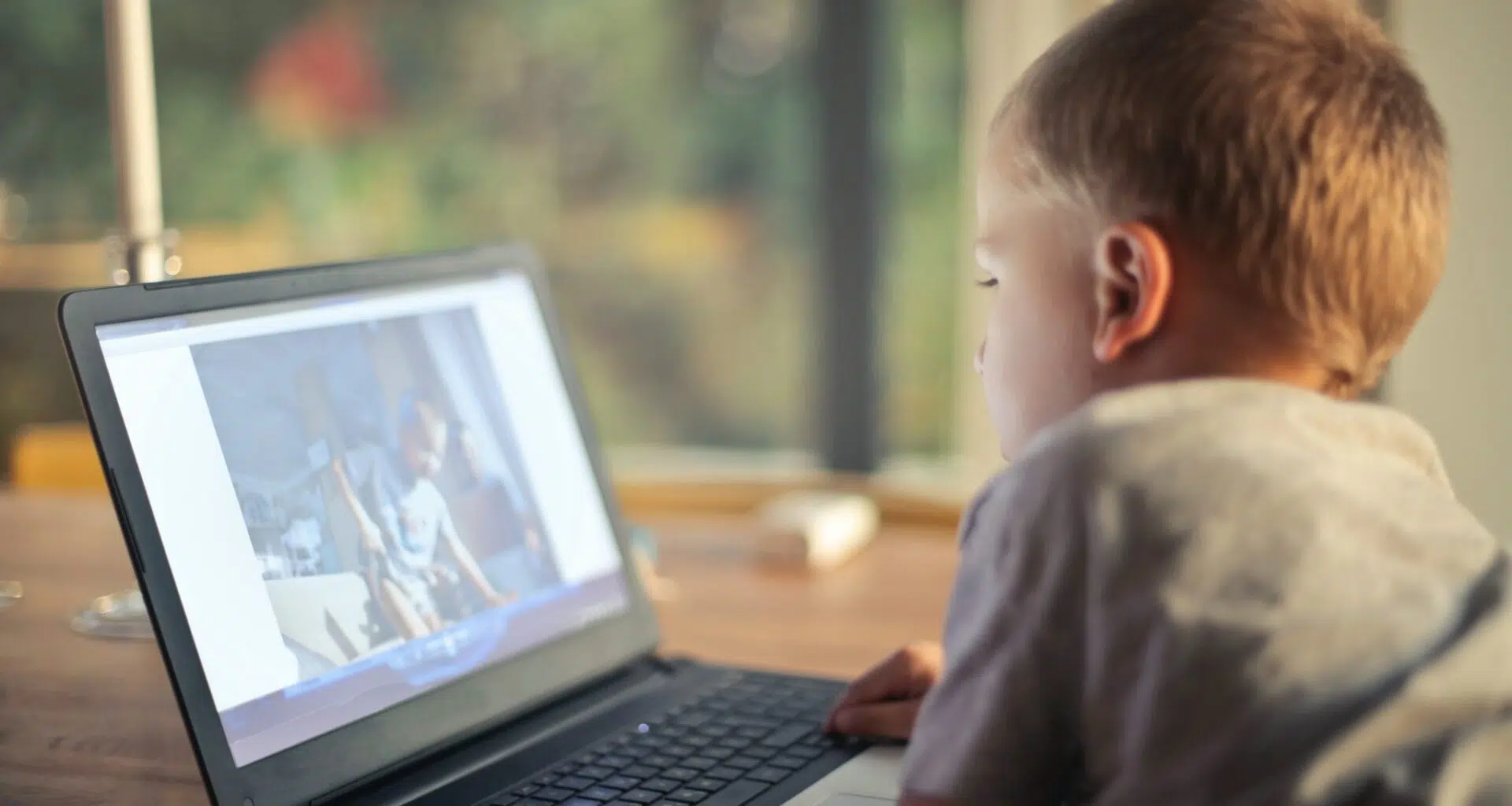 Em imagem, menino navega na internet em seu notebook