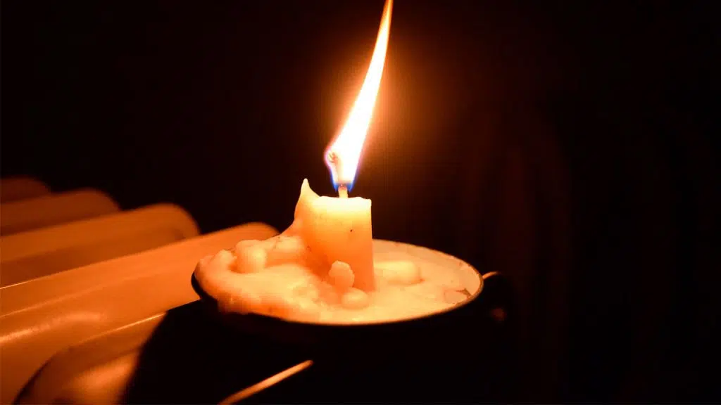 Vela sob um pires iluminando o ambiente, representativa da quantidade de luz emitida por uma vela num espaço de um metro quadrado.