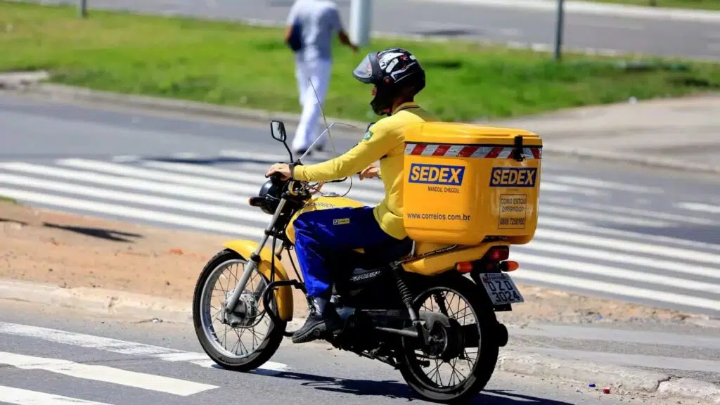 Motociclista fazendo entregas para o sedex hoje.