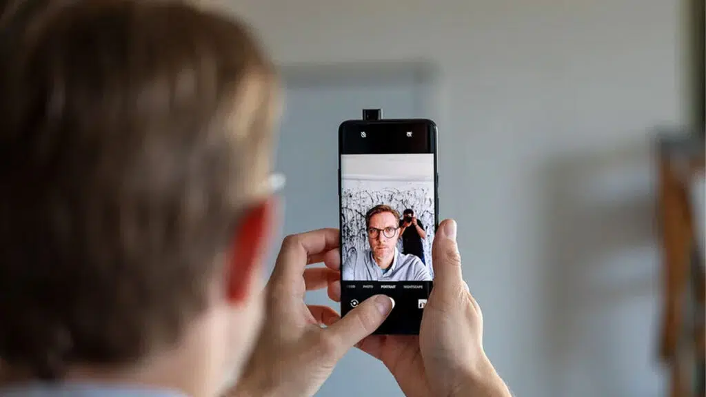 Homem sendo vigiado pelo ombro enquanto usa celular