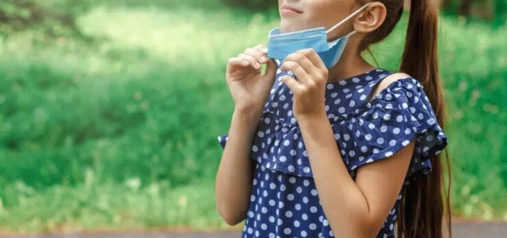 Menina tirando máscara pois está protegida contra a covid-19