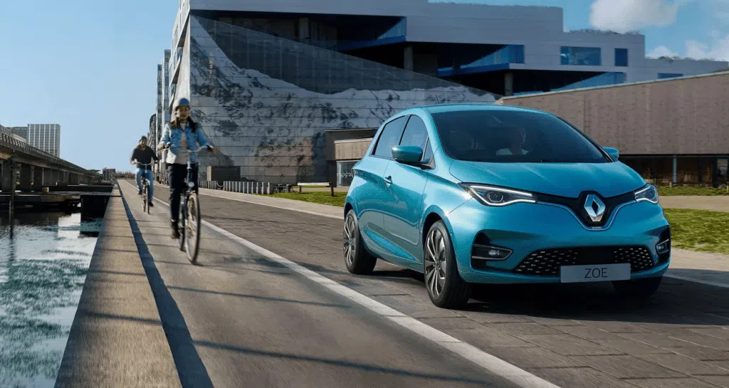 Imagem de divulgação de um renault zoe e-tech azul em uma rua ao lado de dois ciclistas.