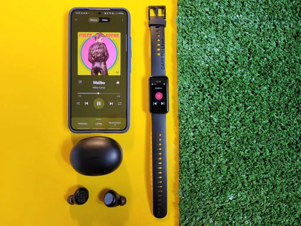 Realme band 2 em cima de fundo amarelo ao lado de grama com galaxy s22 e realme buds q2