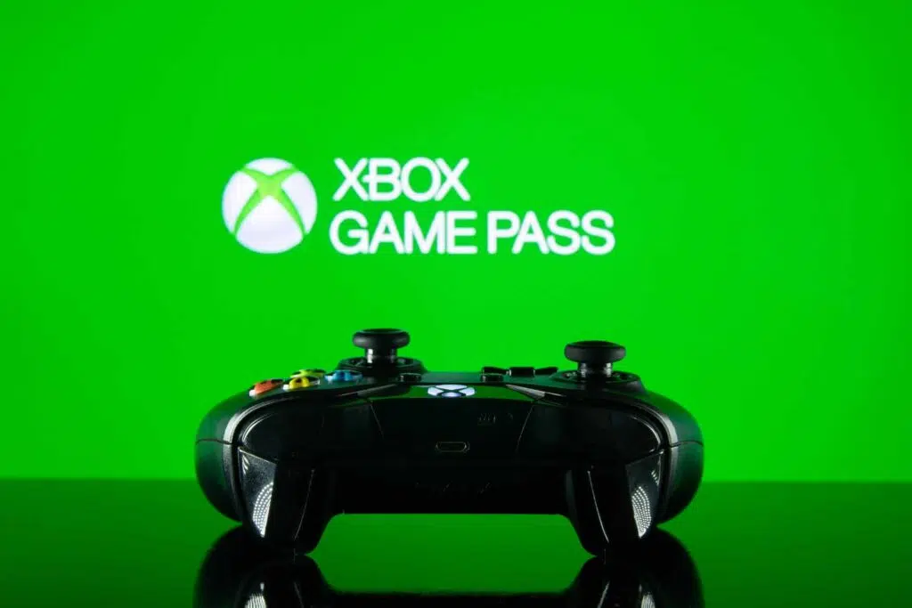 Controle de xbox com a logo do xbox game pass no fundo