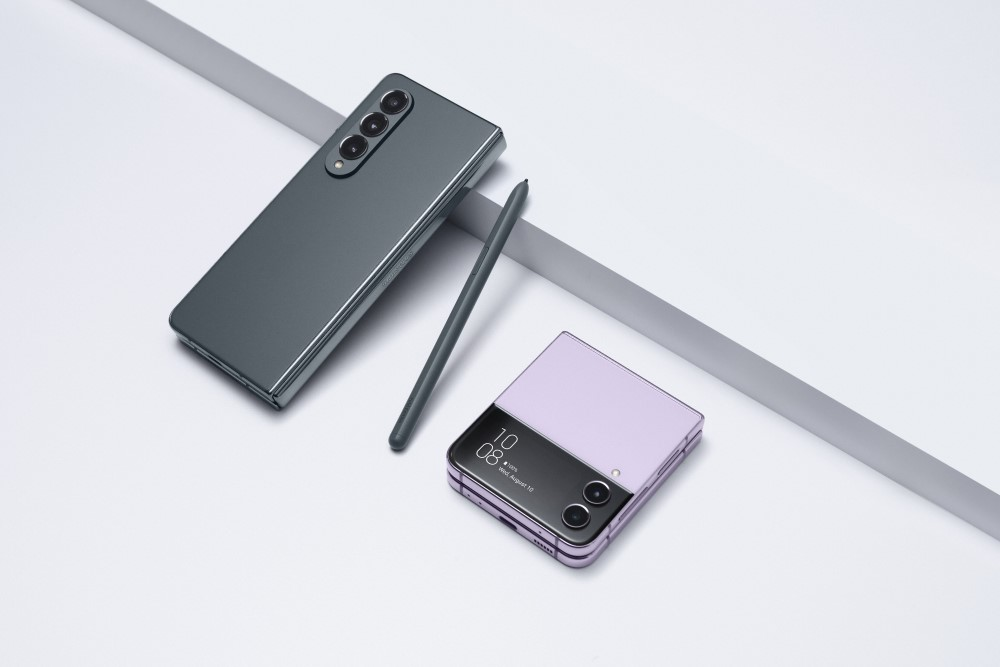 Celulares fold t alt celular dobrado em cor lilás, visto mais à direita, ao lado de outro aparelho, virado com a tela para baixo