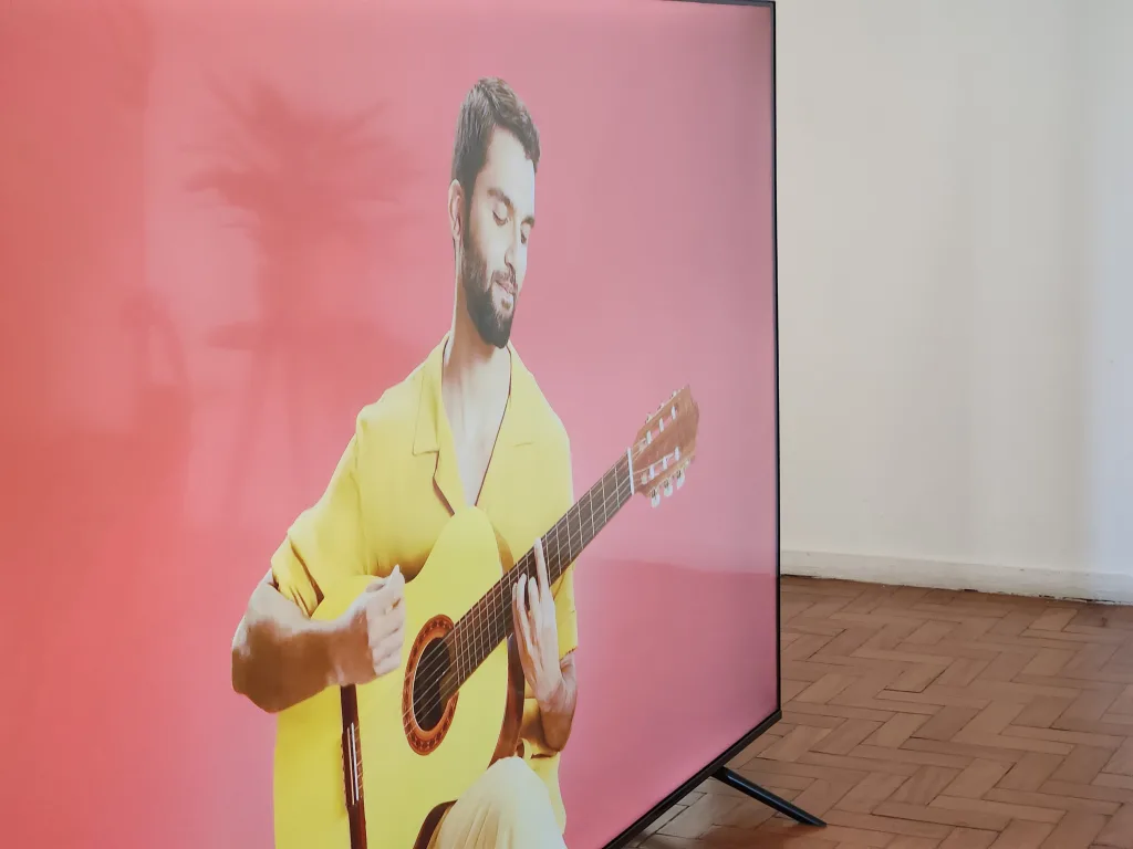 Foto da tcl p635 mostrando o cantor silva usando camisa amarela e violão amarelo em um momento do clipe de fica tudo bem, com a anitta.