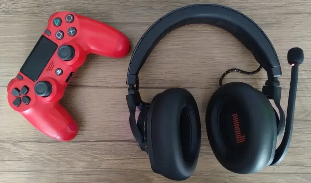 Headset jbl quantum 610 ao lado de dualshock 4 vermelho