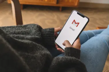 一位女士拿着一部 iphone，屏幕上有 google gmail 应用程序徽标。 Gmail 是 Google 提供的最受欢迎的免费互联网电子邮件服务