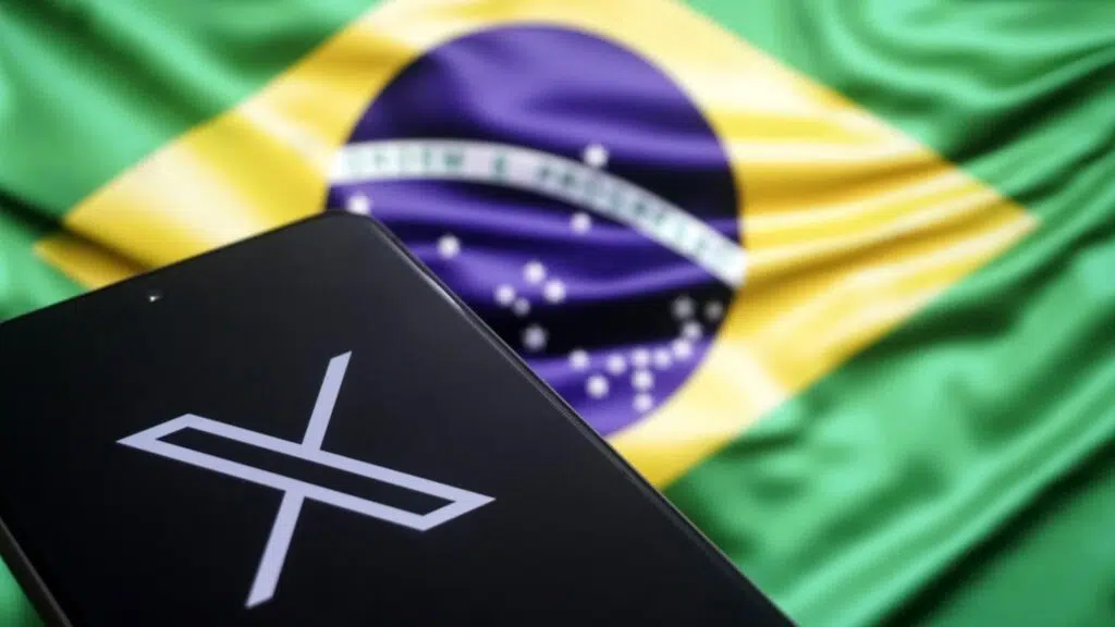 Smartphone com a logo do x com a bandeira do brasil ao fundo